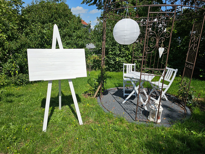 Weiße Staffelei im Garten einer Hochzeitslocation